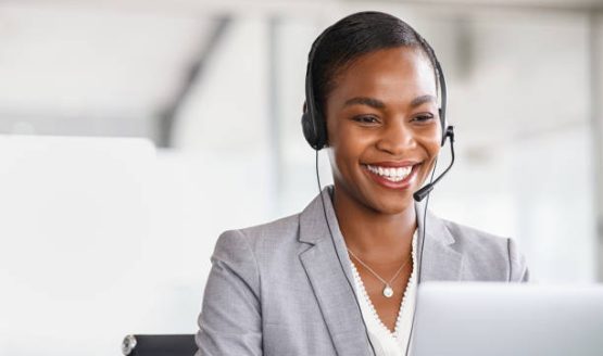 istockphoto-1413763039-612×612 Smiling african american customer care representative working with headset in office. Beautiful black woman telemarketing agent working in call center. Call center agent with headset makinga video call with client.